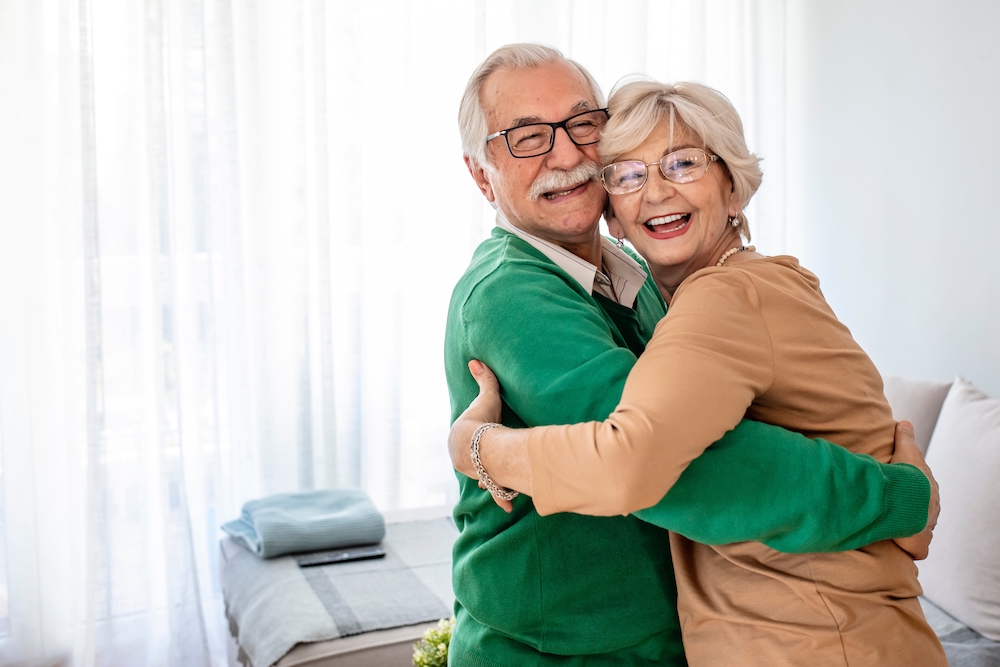 A smiling and happy senior couple share a hug