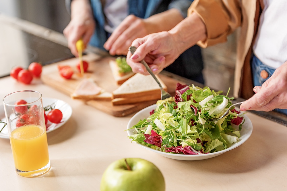 Two senior women preparing a healthy lunch at the dementia care in SaJuan Capistrano