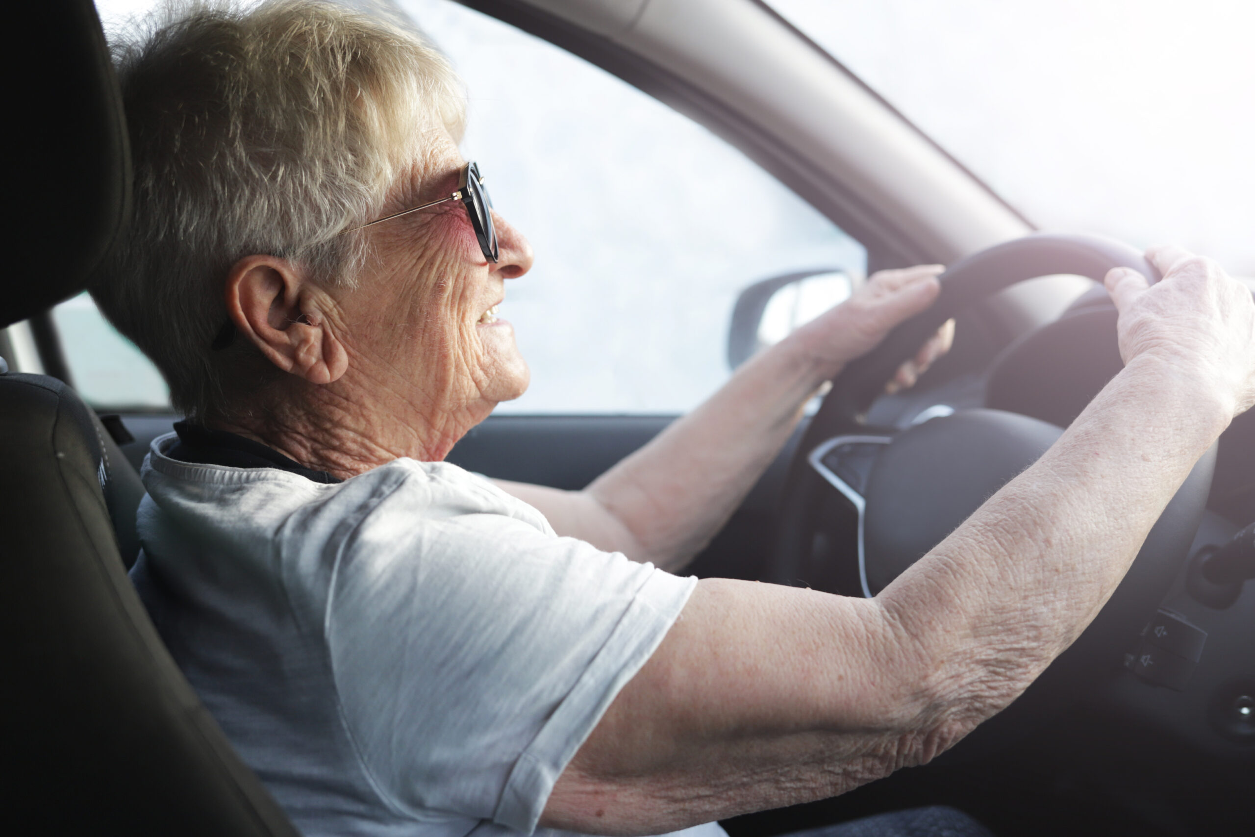 Happy,Senior,Woman,In,Sunglasses,Driving,Automobile. Senior woman driving car wearing sunglasses